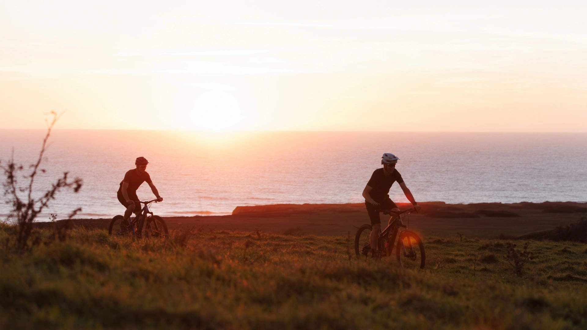 Zwei Mountainbiker bei Sonnenuntergang an der Kueste
